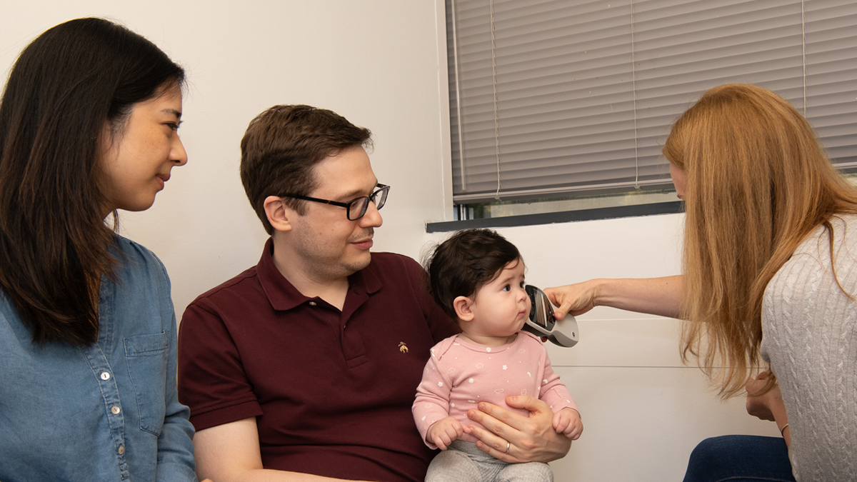 A father and mother are with their baby at the doctor checki… A family takes their infant daughter to get a follow-up hearing test with an audiologist