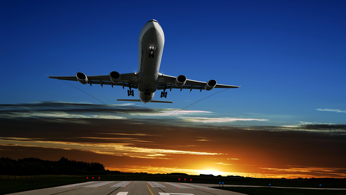 A plane in the air An airplane taking off a runway with the sunset in the background