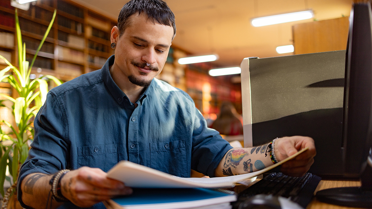 A man sitting at a desk and reading a pamphlet.