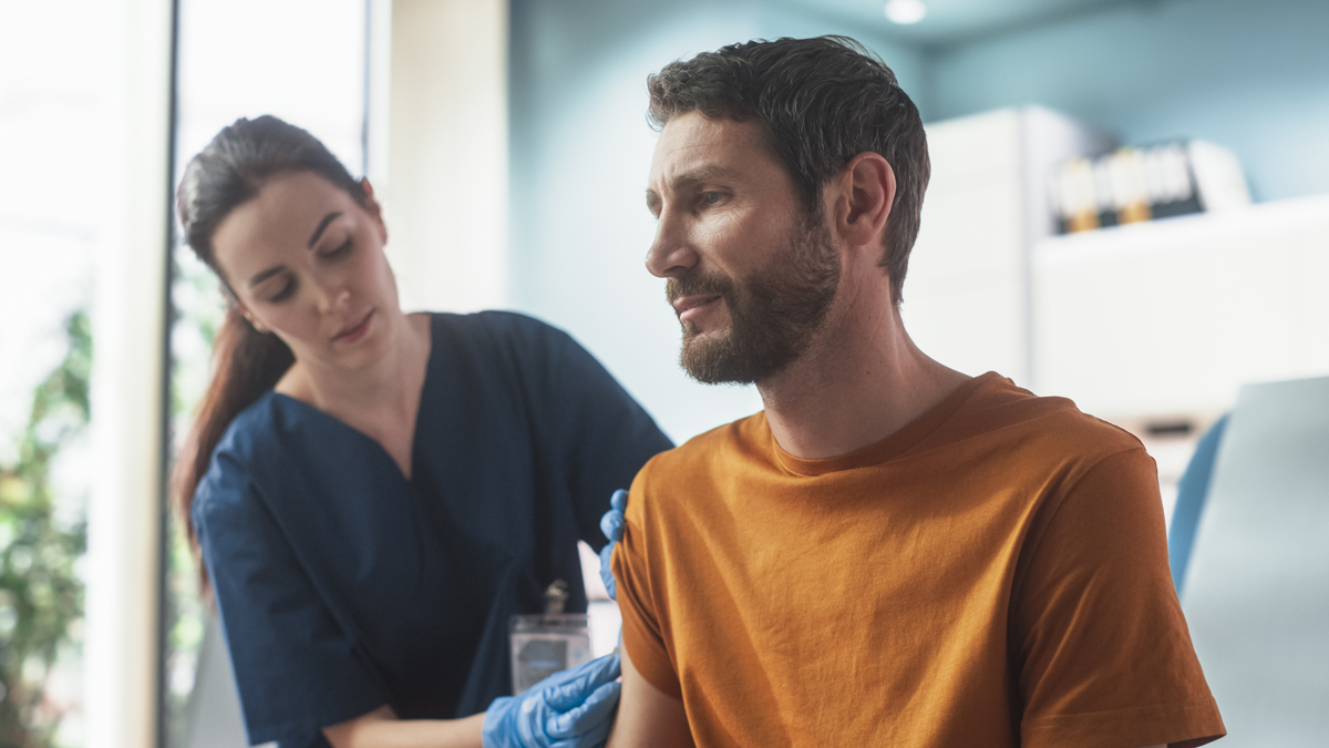 A doctor giving a man a shot in the arm in a doctor's office.