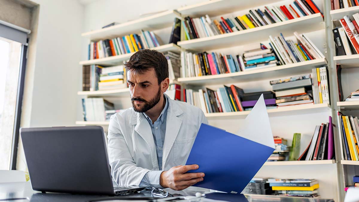 Recommendations for Hepatitis C Screening for Adults Doctor holding medical charts while reviewing hepatitis c screening recommendations on their computer