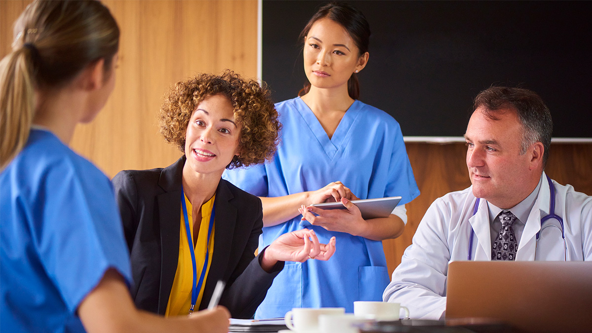 Group of health care professionals seated around a table discussing hepatitis outbreaks