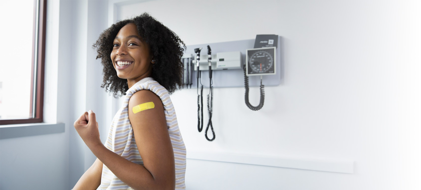 Smiling woman with a bandage on her upper arm after vaccination