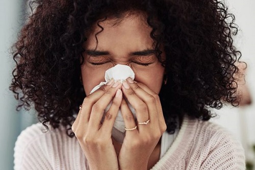 woman-sneezing-cdc-333x500px woman covering her mouth and nose with a tissue while sneezing