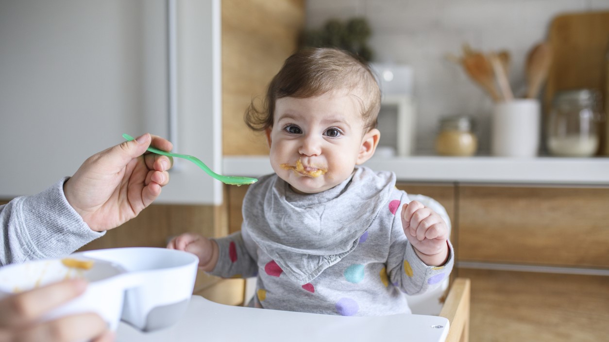 Parent feeding baby with a spoon.