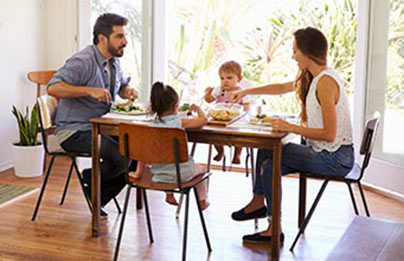 Young children and their parents eating a meal together in their home.