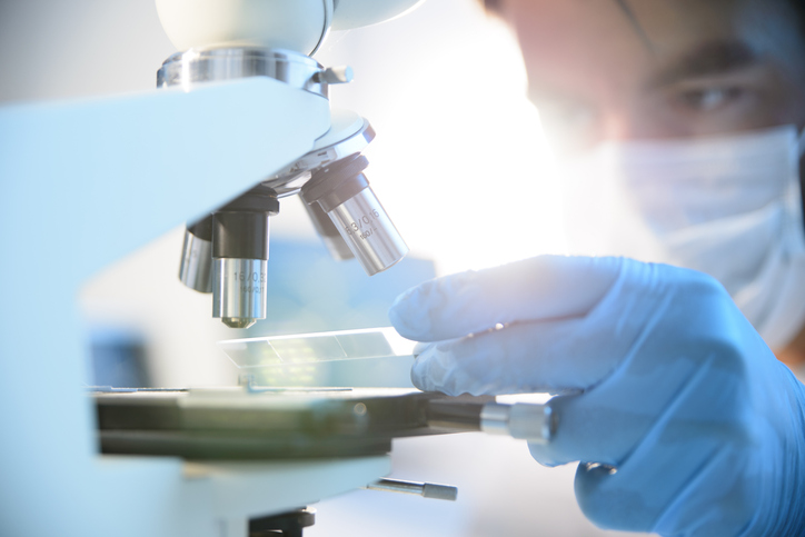 Person examining a specimen under a microscope