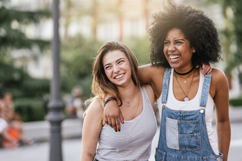 two women walking with their arms slung over the other's shoulder