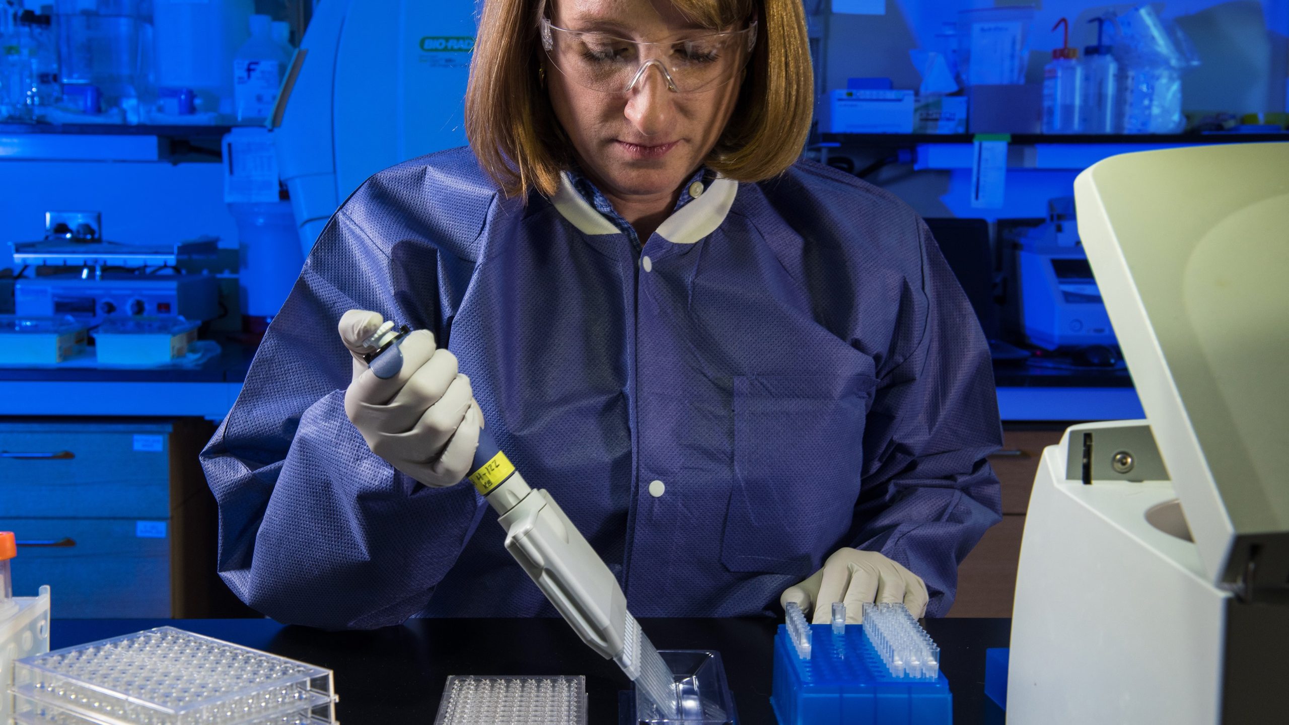 Female researcher holding a pipette in a laboratory.