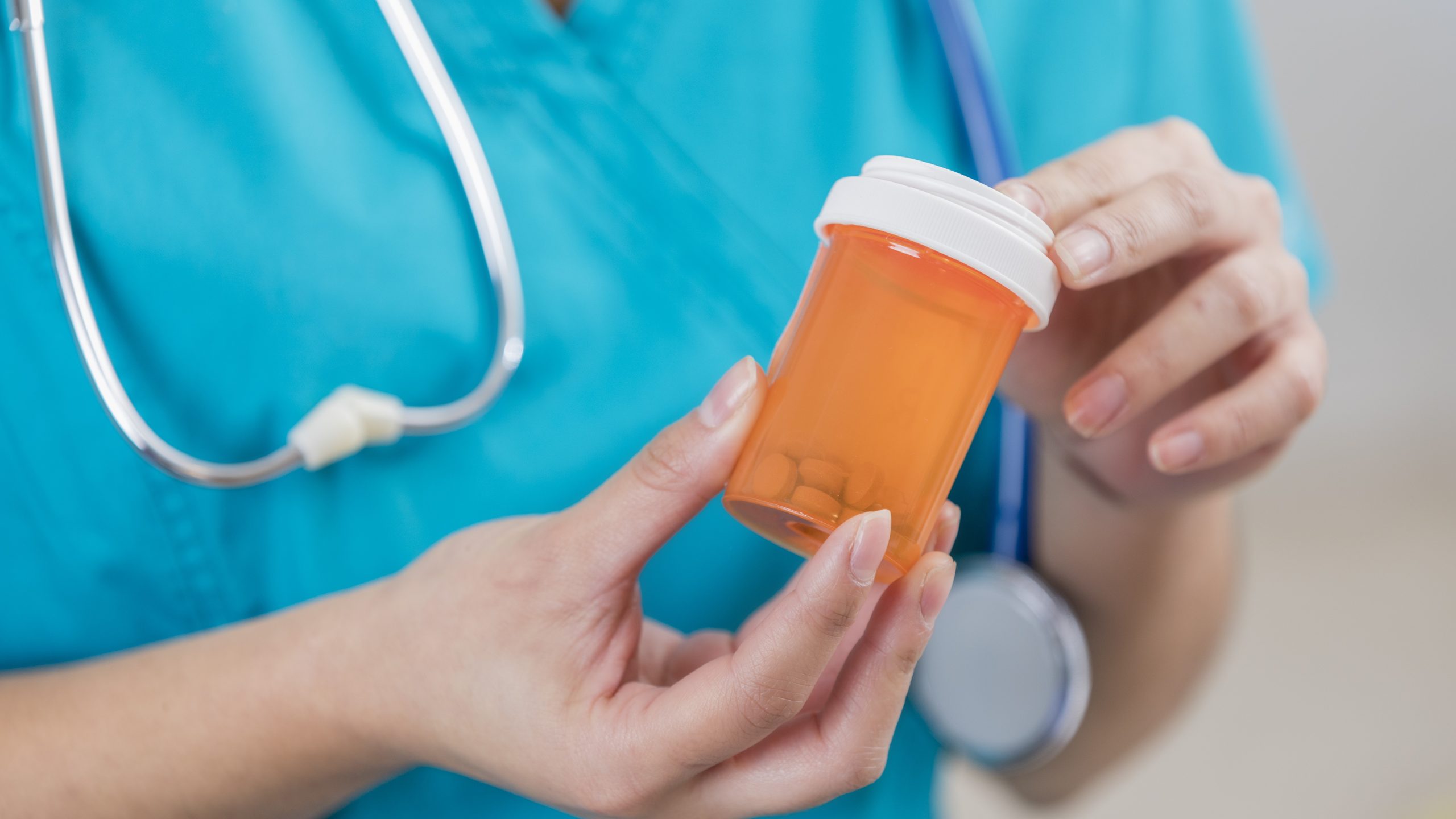 Female health care provider holding an orange pill bottle.