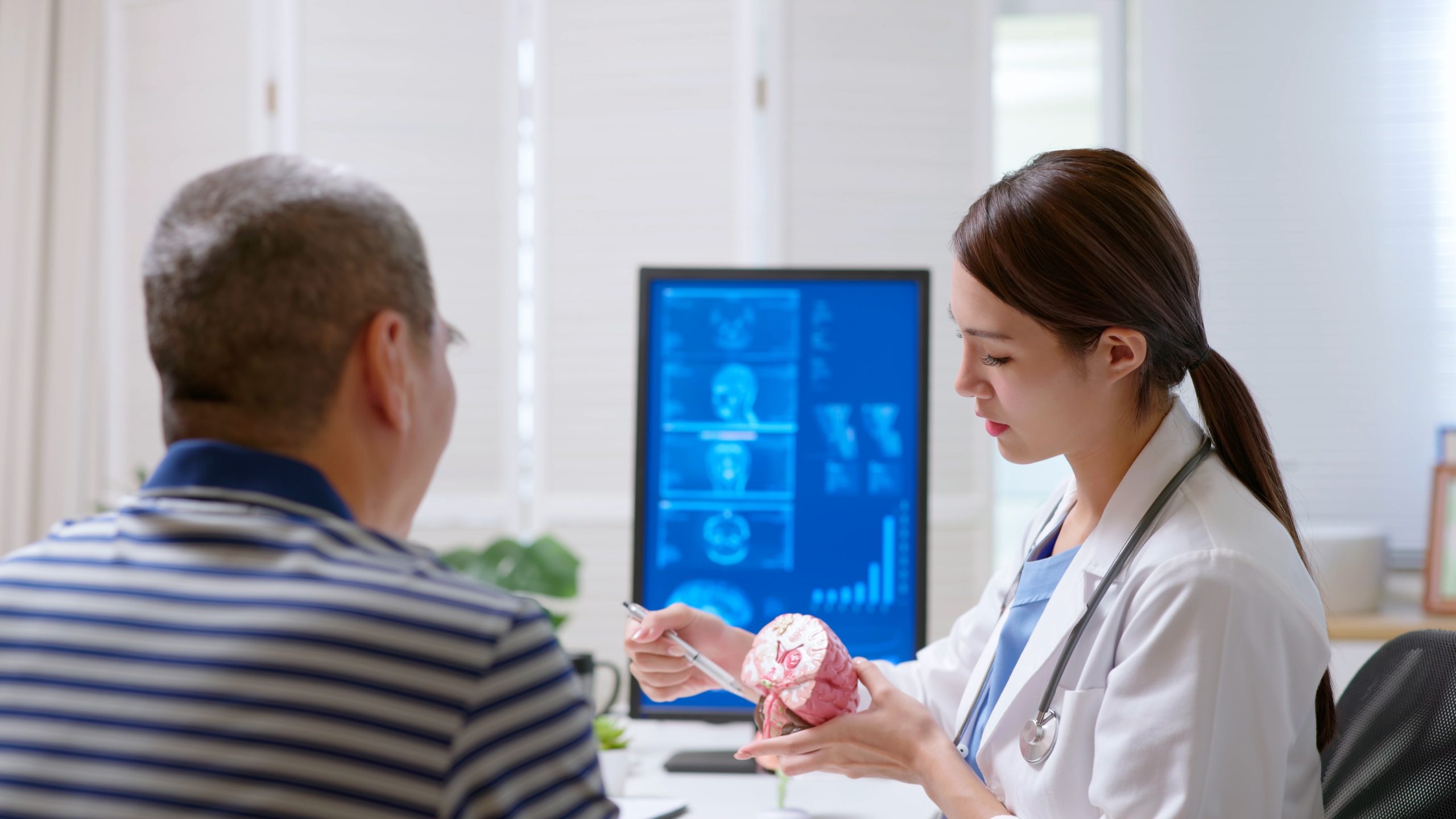 Female health care provider pointing at a brain model with a male patient.