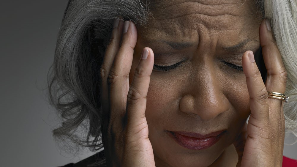 Woman with eyes closed holding her head in pain.