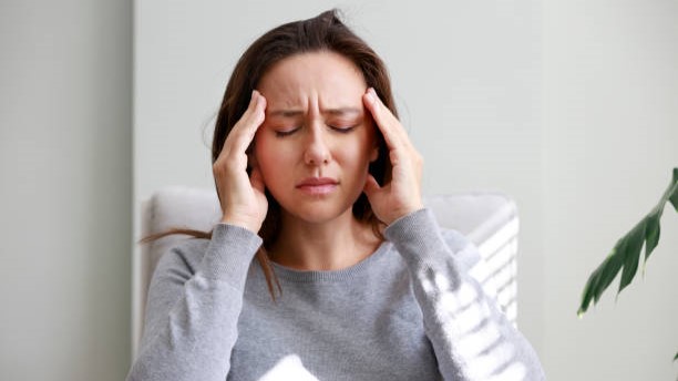 Woman with headache holding both hands to head.
