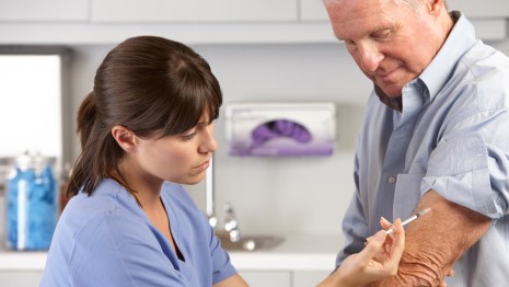 Male receiving a vaccination in his arm from a female healthcare specialist.
