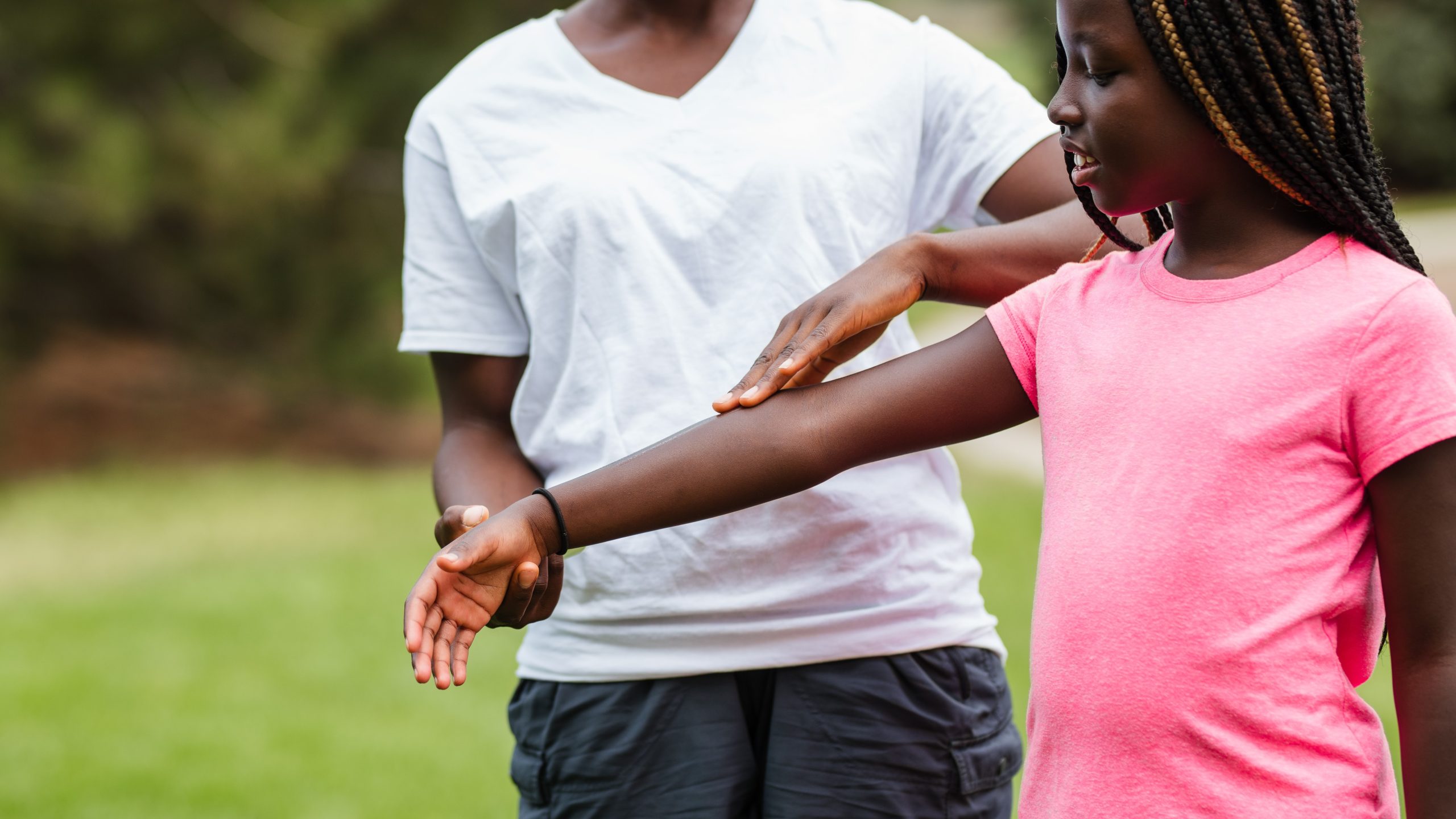 A parent applying insect repellent to his child's arm.