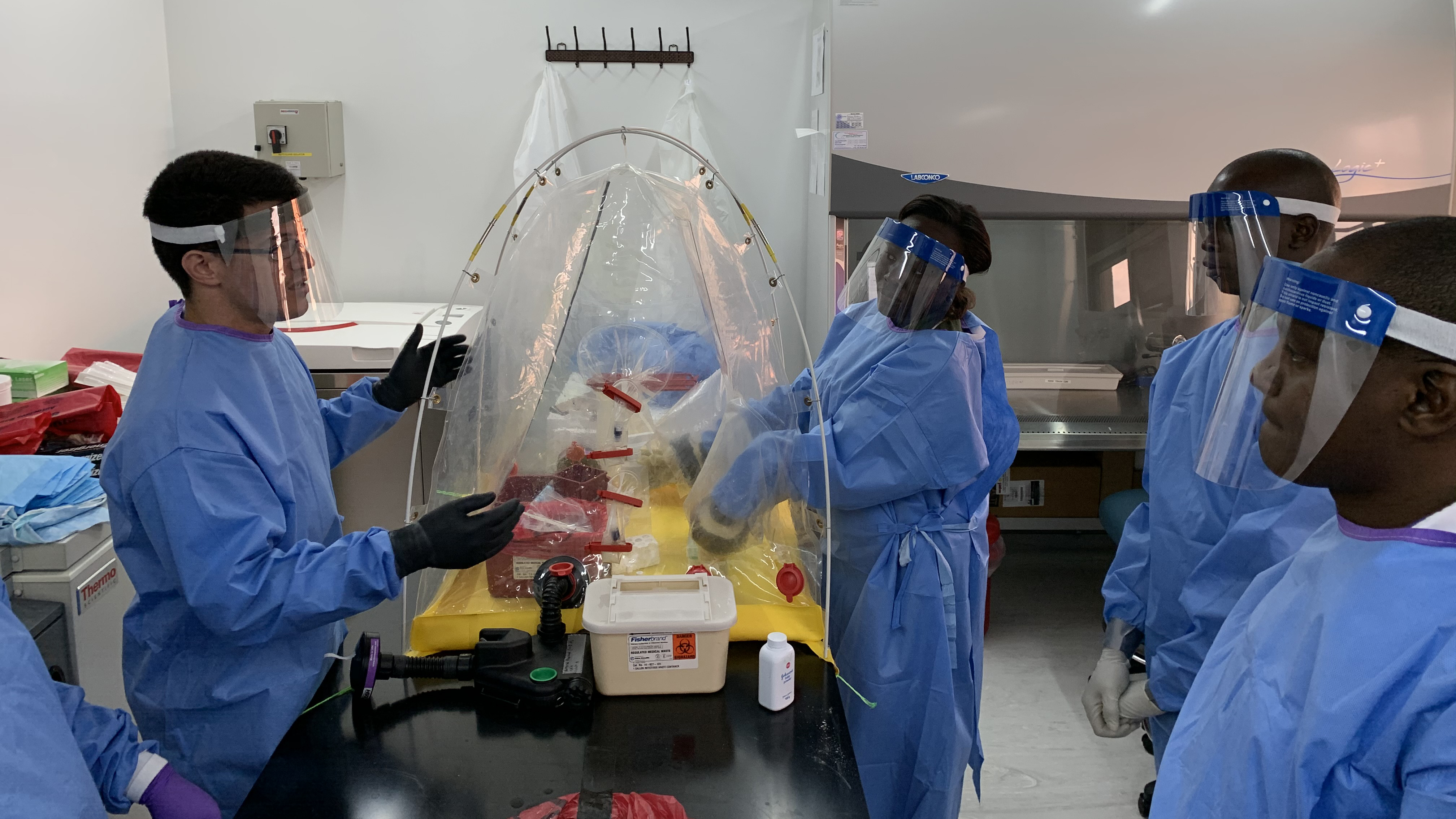 An LLS officer (left) trains laboratory partners on infectious disease testing assays and how to remain safe with protective personal equipment.
