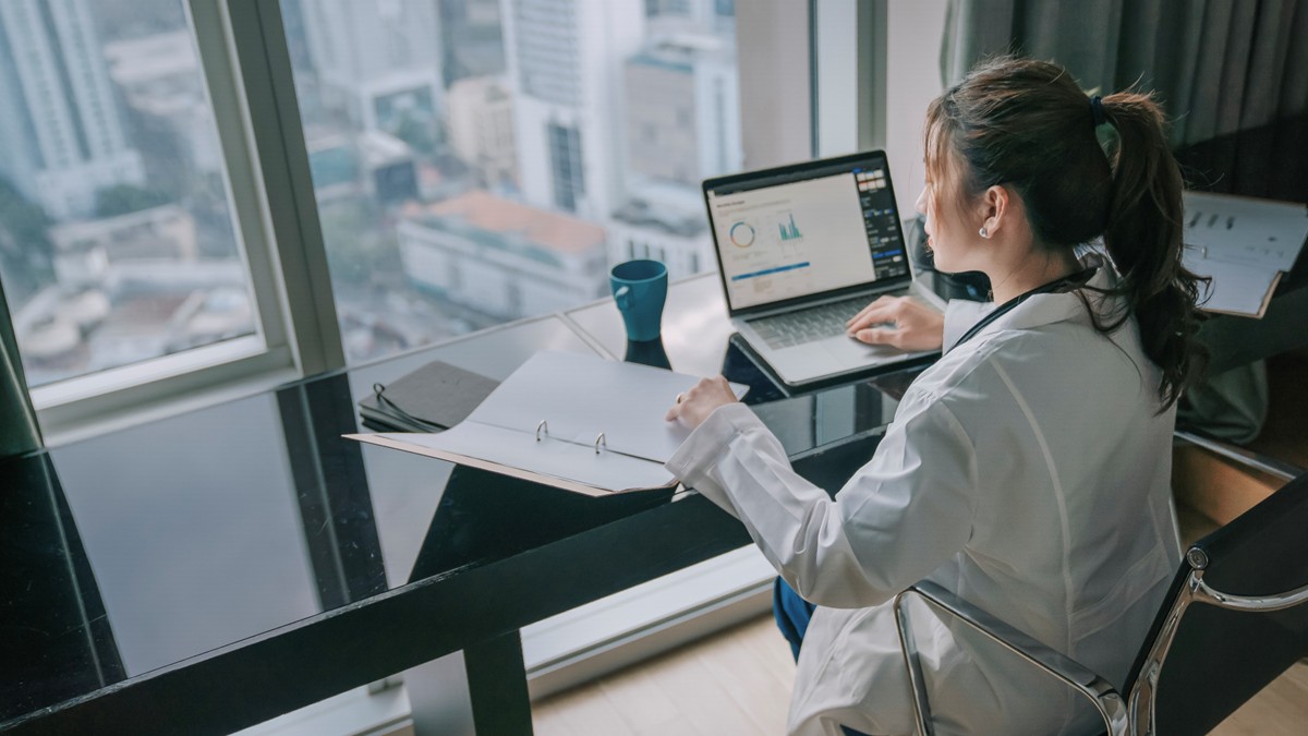 Female HCP works on a medical report on her notebook computer.