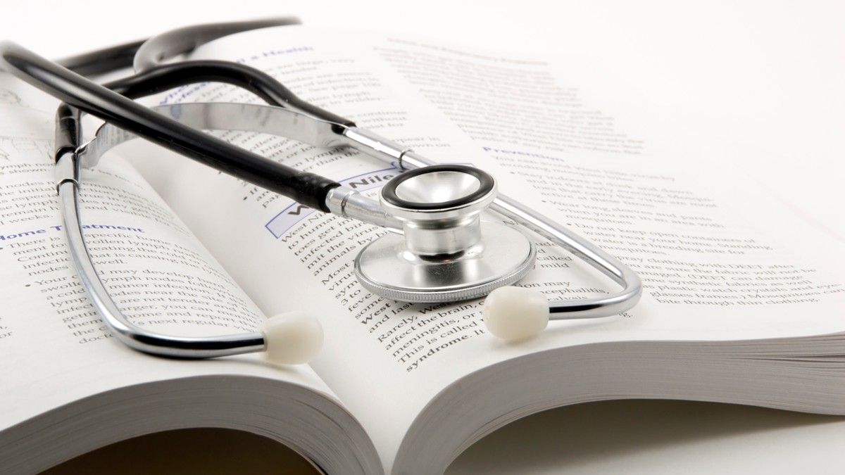 A stethoscope rests on an open reference book.
