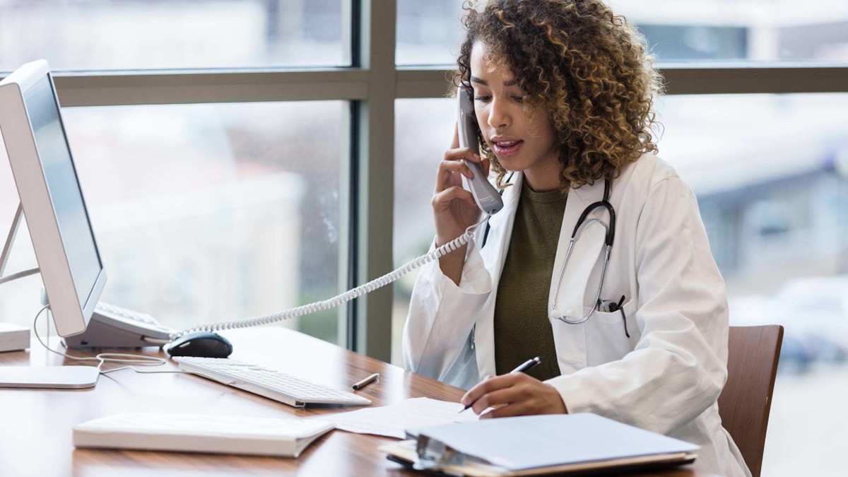 A female doctor talks on the telephone in her office.