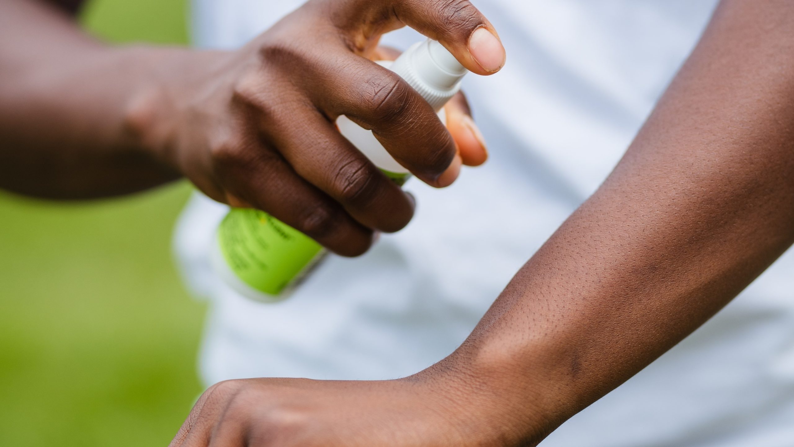 Person applying insect repellent to their arm.