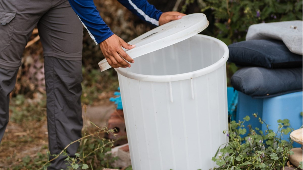 Cover bucket Person covering a bucket to keep mosquitoes from laying eggs in standing water.