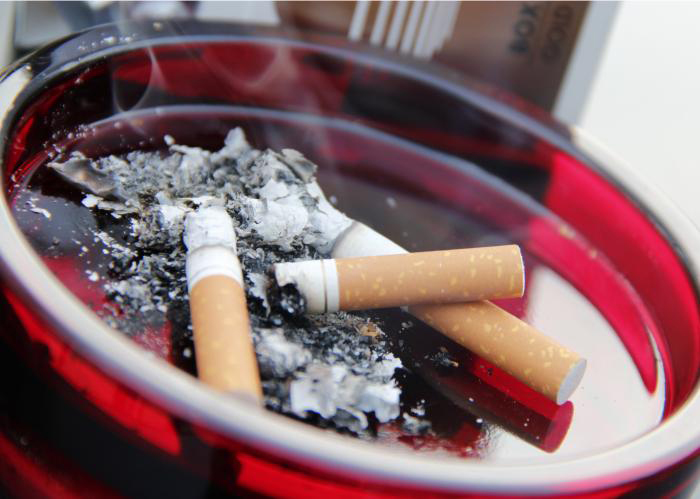 phapproach03 A bright red ashtray filled with smoldering cigarettes and ashes.
