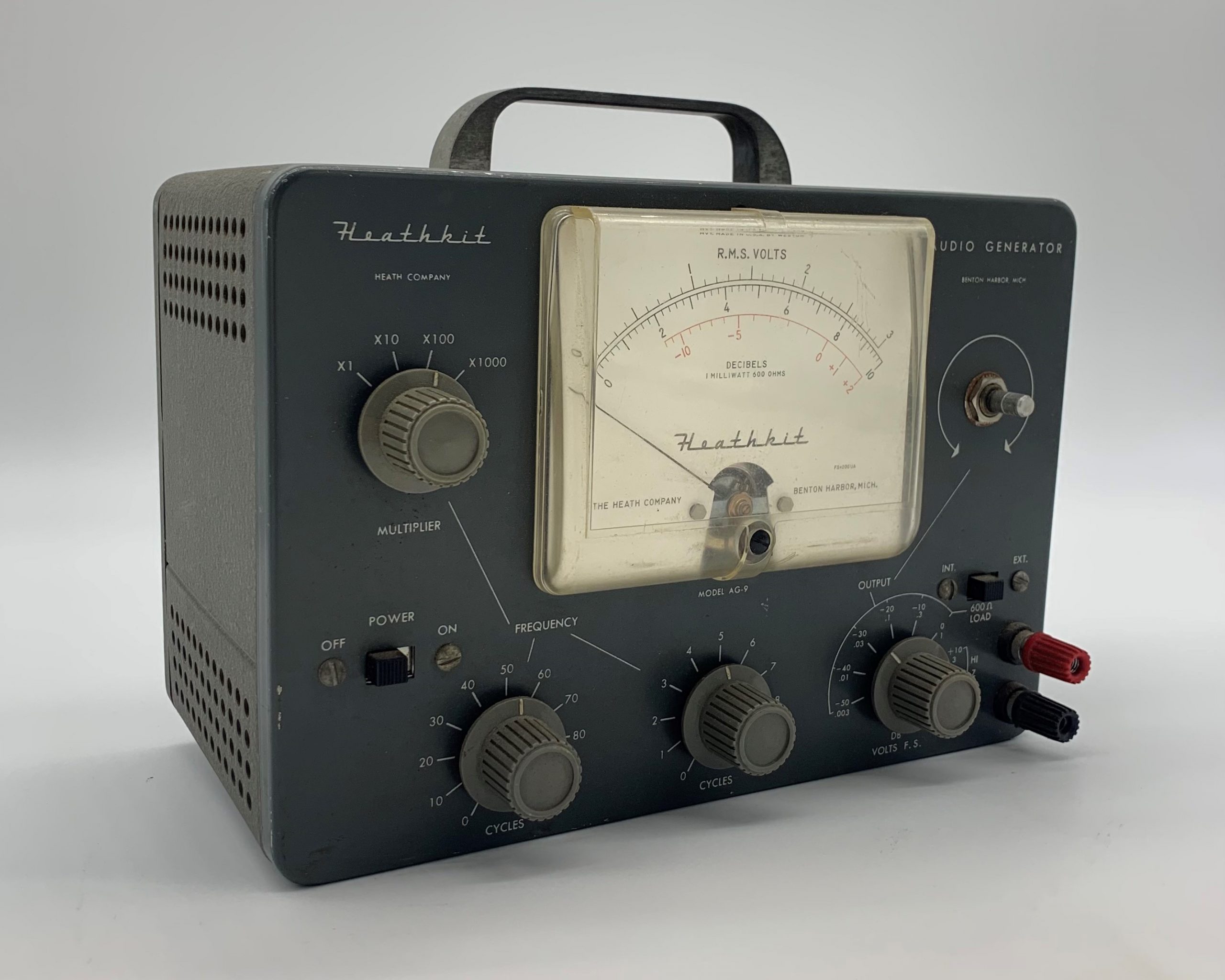 Heathkit Audio Generator consists of a dark gray box and a frequency monitor with indicator needle. The kit has knobs to adjust the audio input&rsquo;s multipliers, cycles, frequency, and voltage.