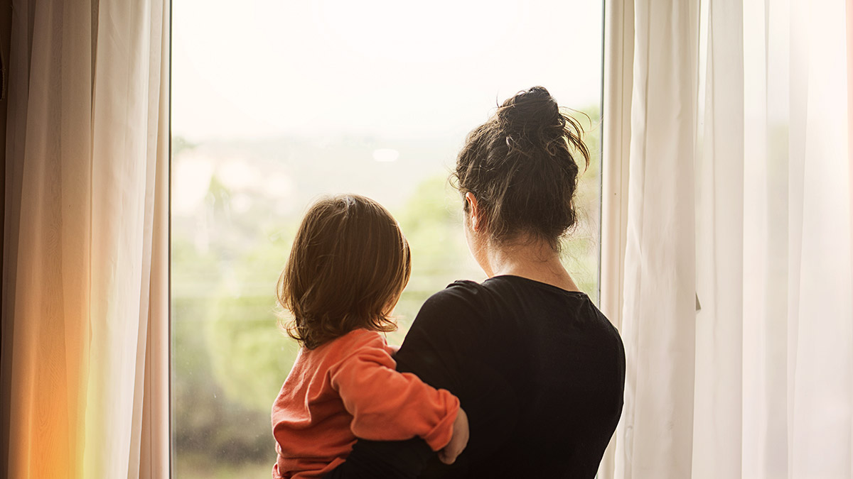 Mother and daughter looking out a window
