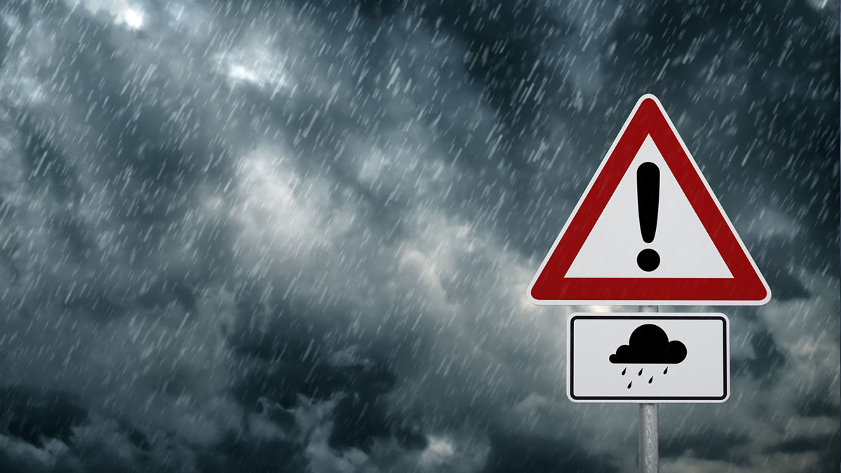 Flood warning sign with stormy skies in backdrop.