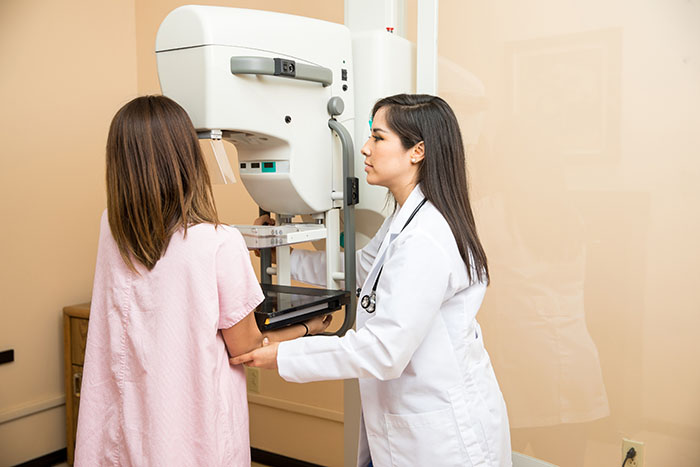 Doctor helping patient get a mammogram El paciente de ayuda del doctor consigue una mamografía