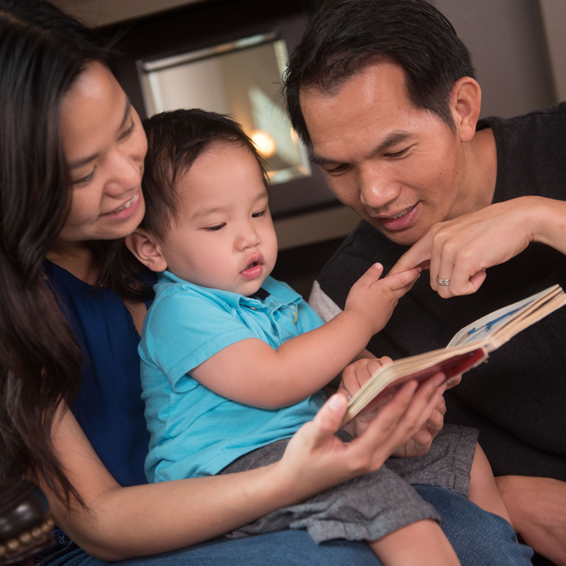Toddler looking at a book with her families