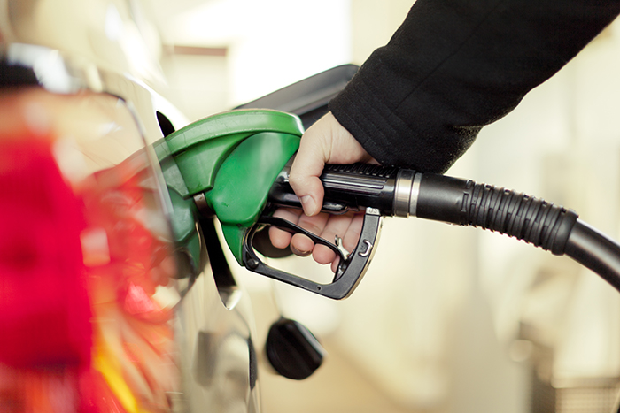 Image of an adult putting gas in a car. 