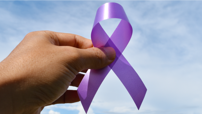Hand holds purple ribbon (for drug overdoses) against sky