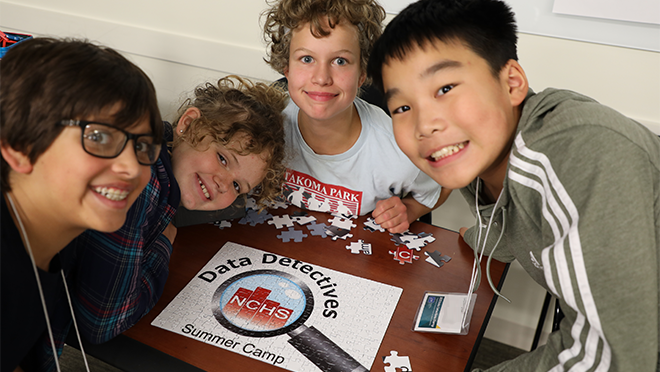 4 kids smiling enjoying solving a puzzle.
