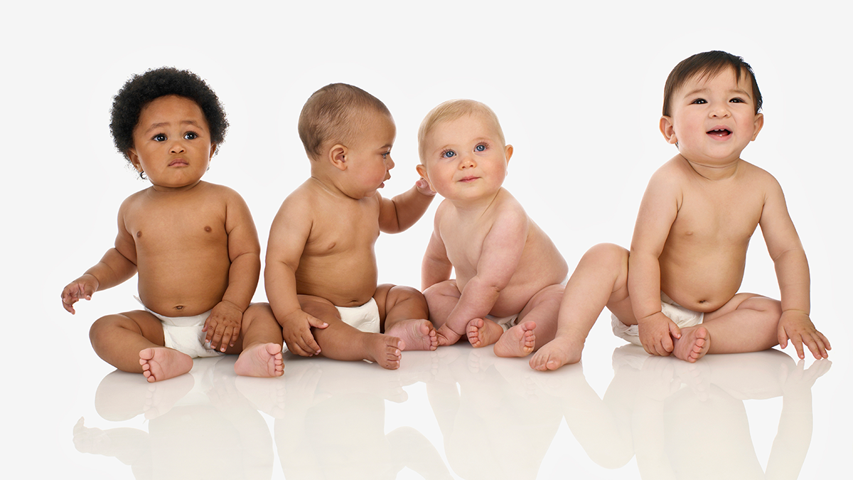 A group of diverse babies in diapers sitting together.