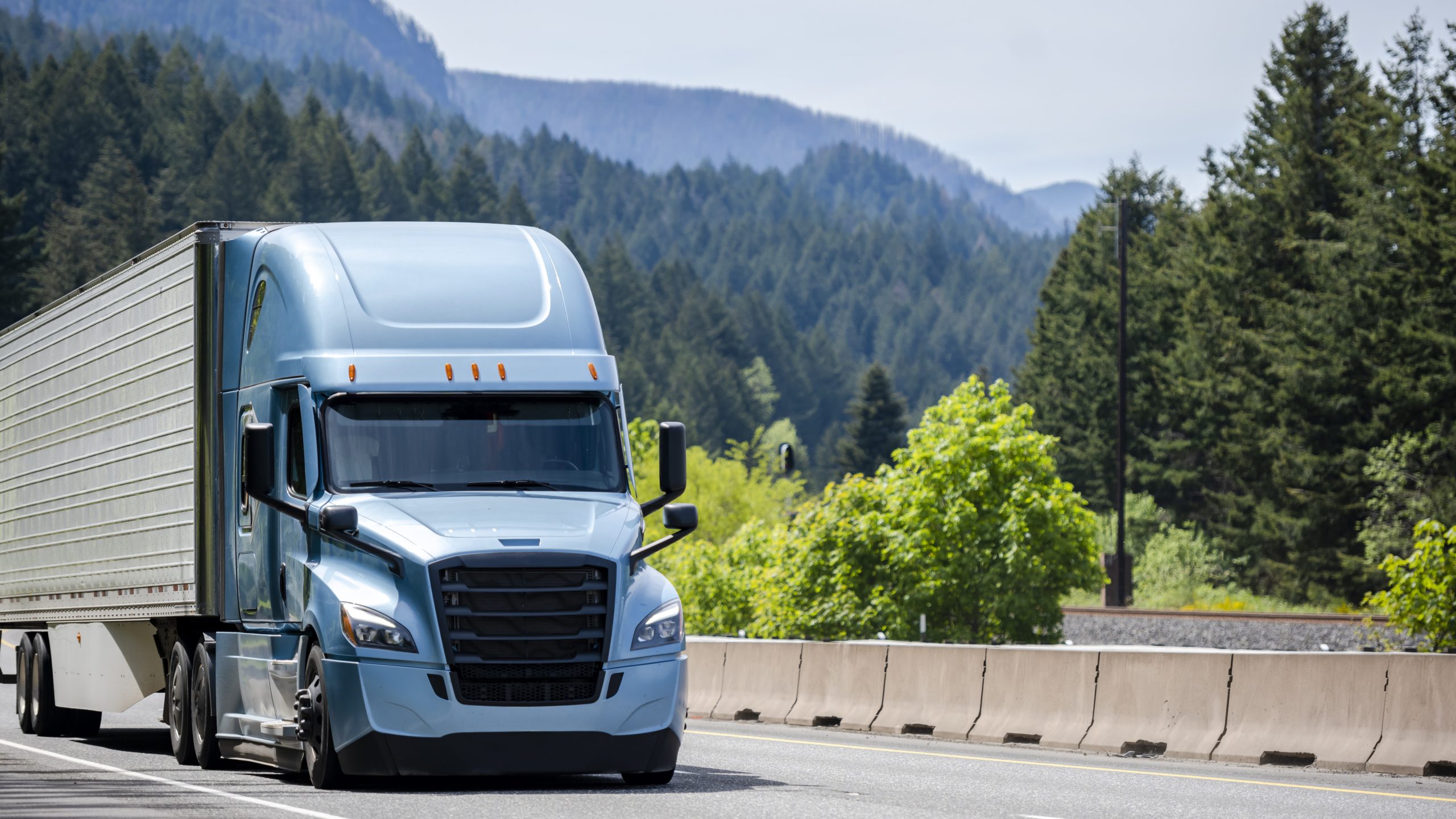 A blue semi-tractor trailer driving through the mountains.