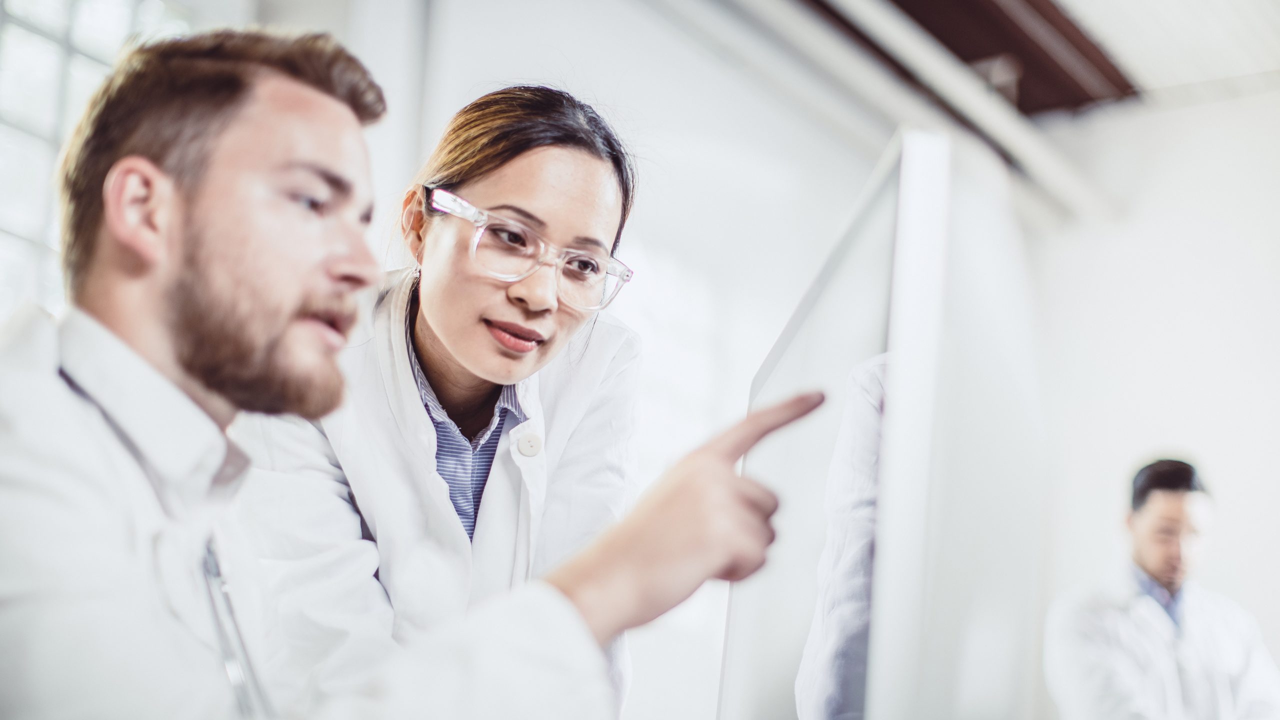 Clinical discussion A physician pointing to an x-ray screen with another physician looking at the screen.