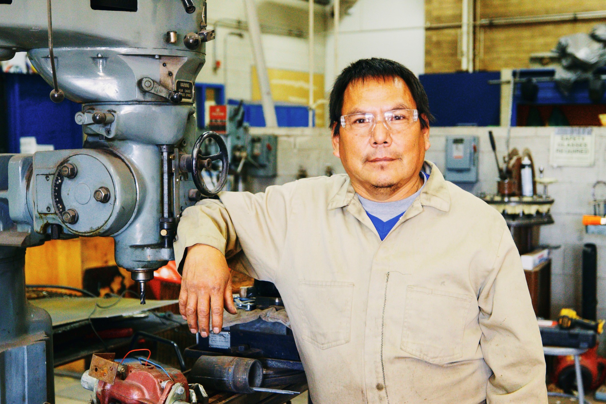 Photo of a male American Indian worker in front of machinery.