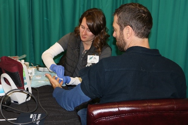 Dr. Scott providing a cholesterol and glucose screening.