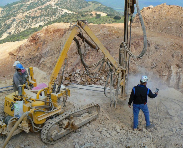 A NIOSH industrial hygienist measuring silica-containing respirable dust levels in the drilling area at a surface stone quarry. Photo from NIOSH.