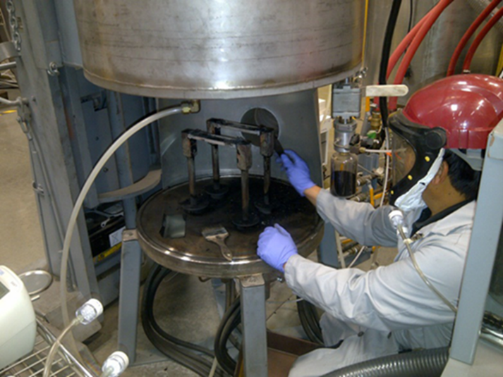 Figure 1. A worker cleaning a nanomaterial reactor with a local exhaust hood to capture particles. Photo by NIOSH