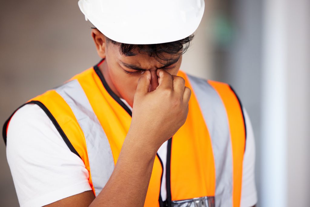 image of construction worker holding their face in his hand.