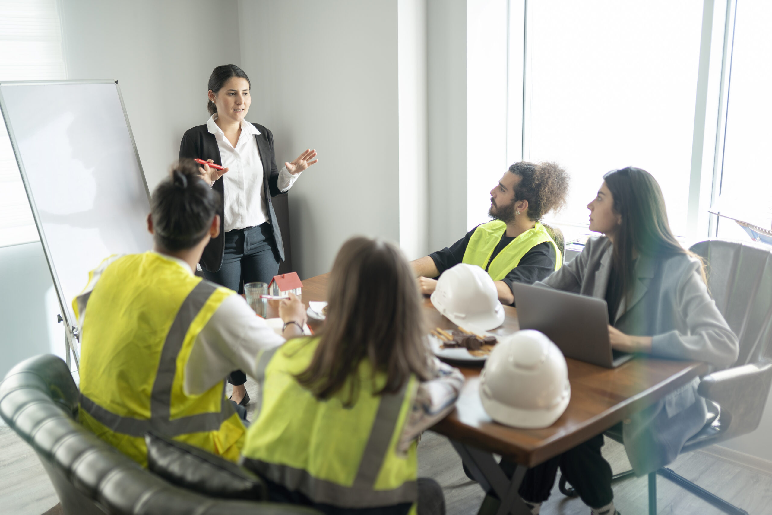 Construction workers sitting around a table looking at an instructor.