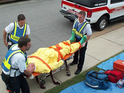 Three EMS workers moving a patient on a gurney.