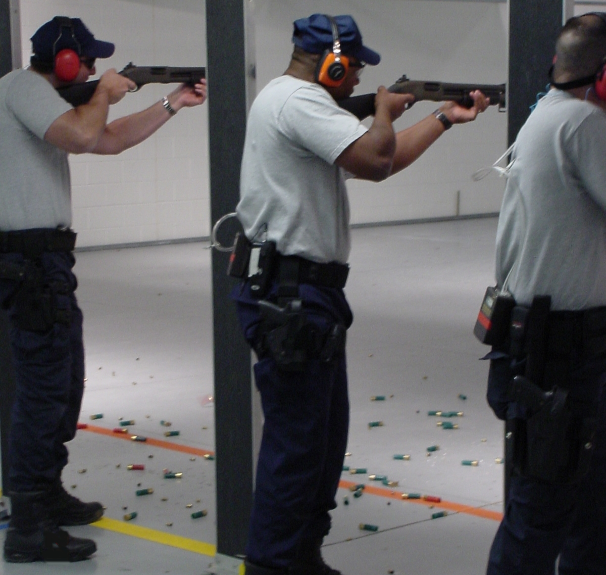 Photo of three men at an indoor firing range.