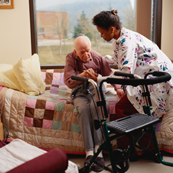 Photo of nursing assistant helping an elderly patient get up.