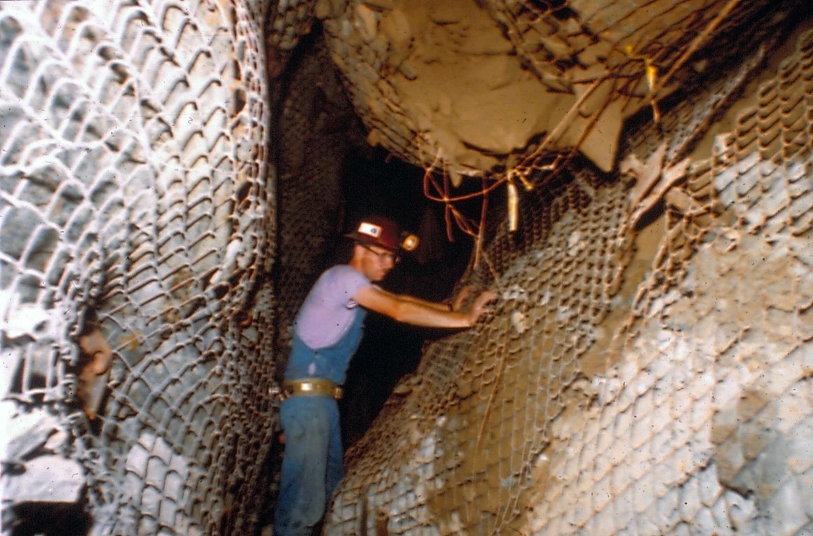 NIOSH researcher Doug Scott inspecting the aftermath of a rock burst at a deep underground hardrock mine in North Idaho. Prior to the rock burst, this drift would have been approximately 15’x15′.