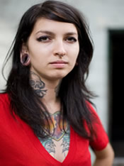 Photo of a woman with tattoos on neck and chest.