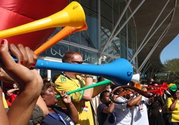 Fans blowing vuvuzelas in stands.