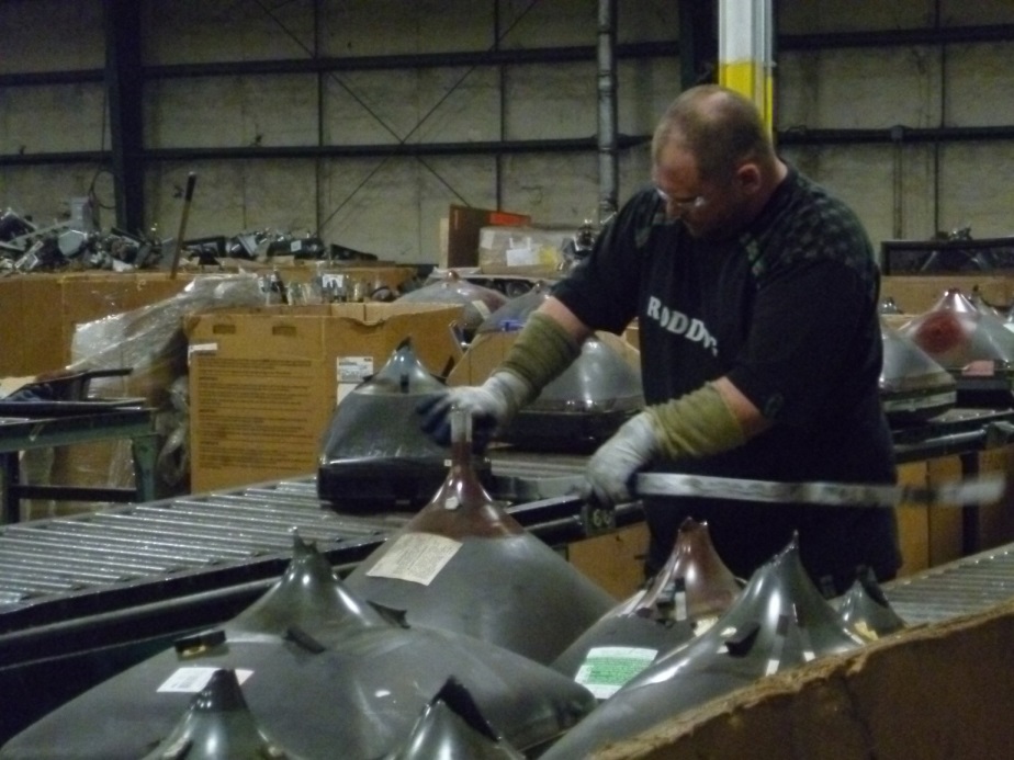 Employee manually dismantling cathode ray tubes from televisions
